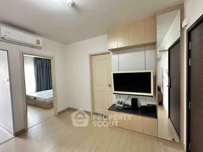 Modern living room with built-in TV unit and wooden flooring in a cozy apartment.
