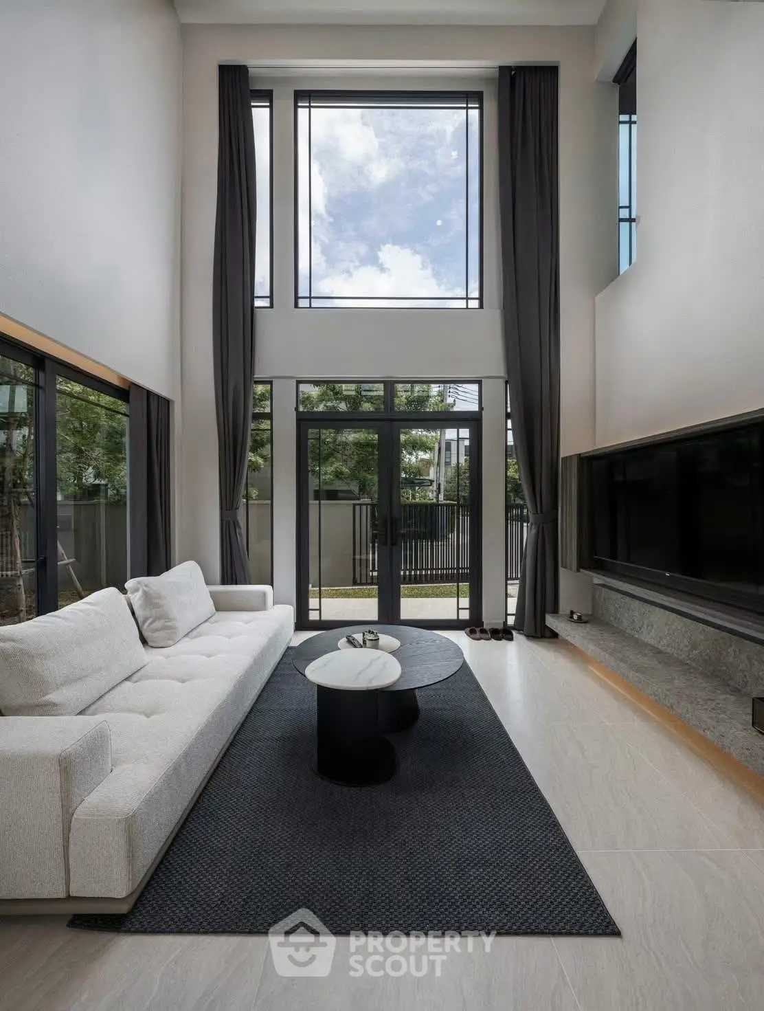 Luxurious modern living room with high ceilings and large windows offering a stunning view.
