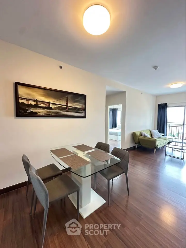 Modern dining area with glass table and stylish chairs in open-plan living space.