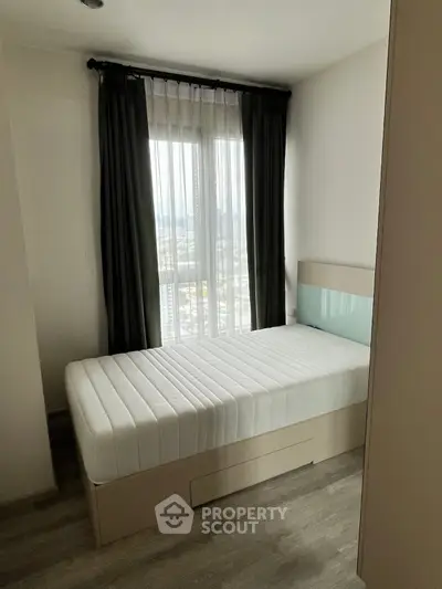 Cozy bedroom with single bed and large window offering natural light and city view.