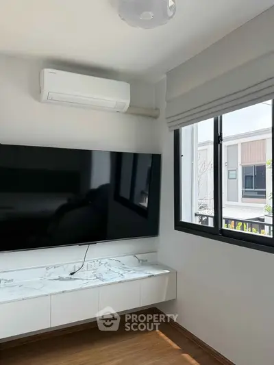 Modern living room with sleek TV setup and natural light from window