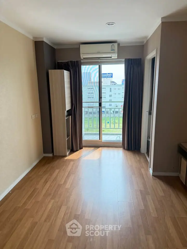 Spacious living room with wooden flooring and balcony access in modern apartment.