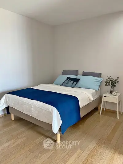 Cozy bedroom with modern decor and wooden flooring, featuring a comfortable bed and stylish side table.