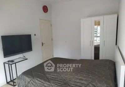 Cozy bedroom with modern decor, featuring a sleek wardrobe and wall-mounted TV.