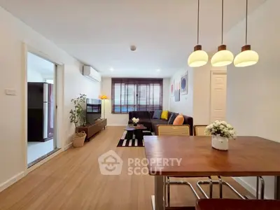 Modern living room with stylish decor and dining area, featuring wooden flooring and ambient lighting.