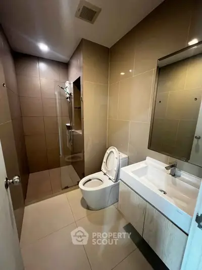 Modern bathroom with sleek fixtures and spacious shower in contemporary apartment.