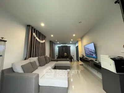 Spacious living room with modern gray sofa and large TV, perfect for relaxation and entertainment.