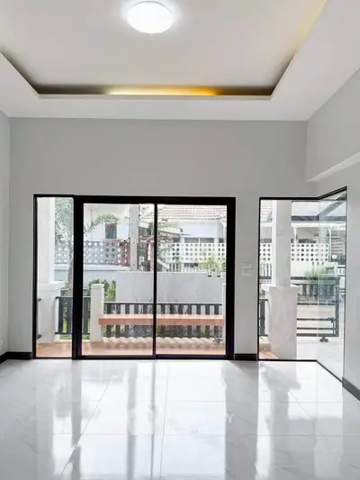 Spacious modern living room with large windows and balcony access, perfect for natural light and outdoor views.