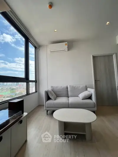Modern living room with large window and city view, featuring a cozy sofa and stylish coffee table.