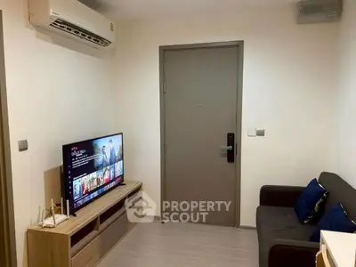 Cozy living room with modern TV setup and comfortable seating in a compact apartment.