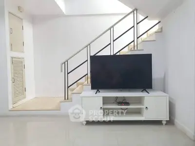 Modern living room with sleek staircase and TV setup, perfect for contemporary living.