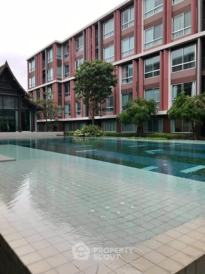 Modern apartment building with a serene pool and lush greenery, offering a tranquil living environment.