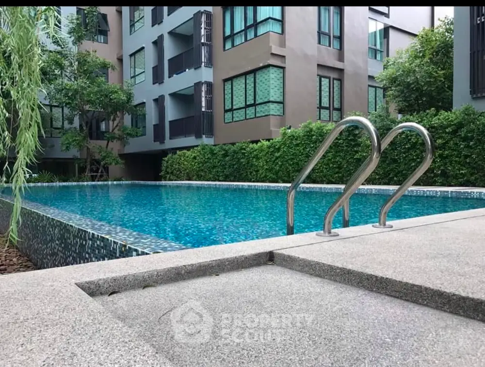 Modern apartment building with a luxurious swimming pool surrounded by greenery.