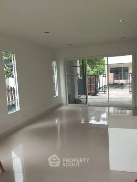 Spacious modern living room with large windows and sliding glass doors leading to a balcony.
