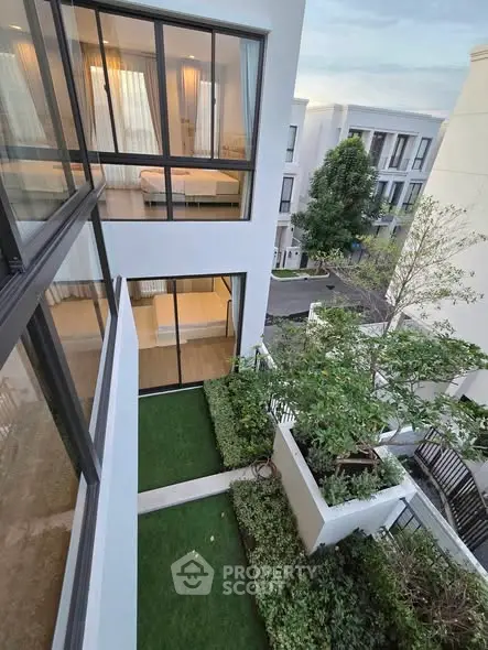 Modern multi-story building with lush green garden and large windows offering a serene view.