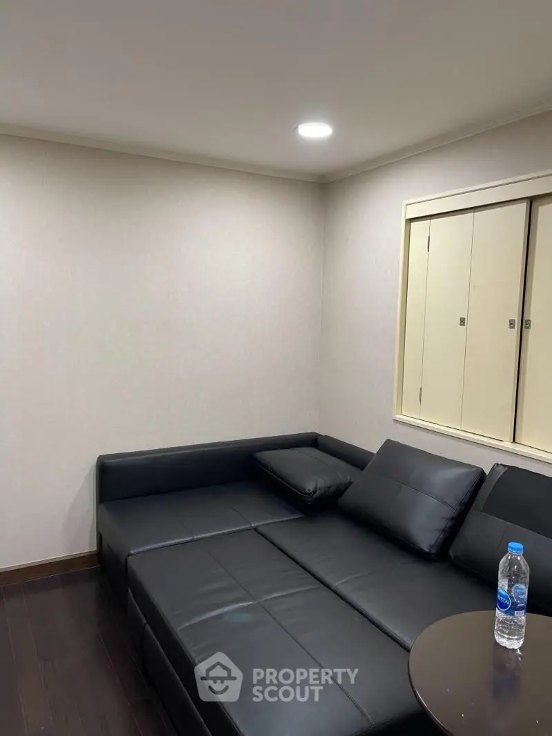 Cozy living room with black leather sectional sofa and wooden flooring