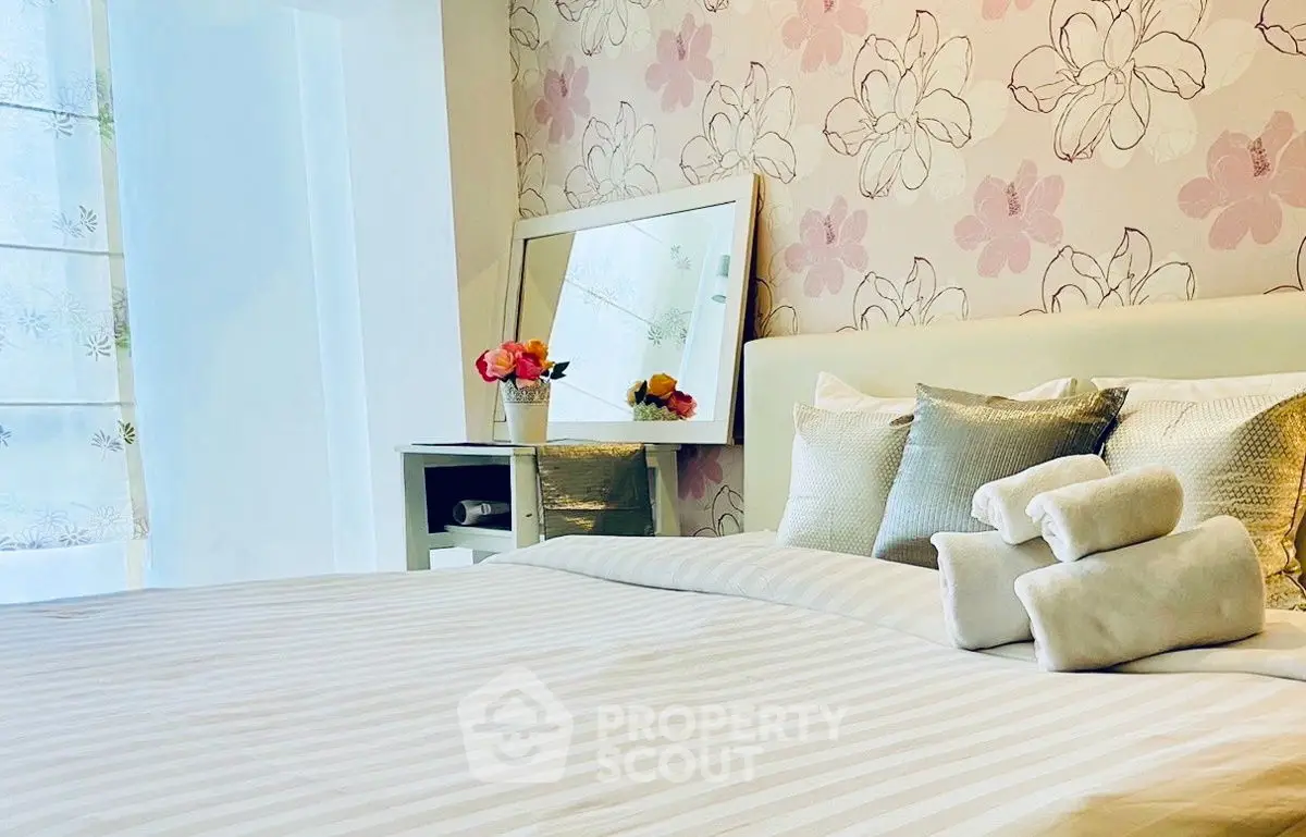 Charming bedroom with floral wallpaper and cozy bedding, perfect for relaxation.