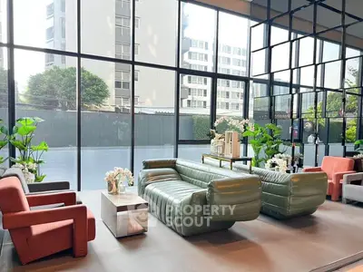 Spacious modern living room with large windows and stylish furniture in urban setting.