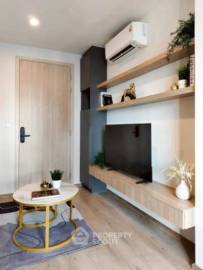 Modern living room with stylish decor, wall-mounted TV, and air conditioning unit.