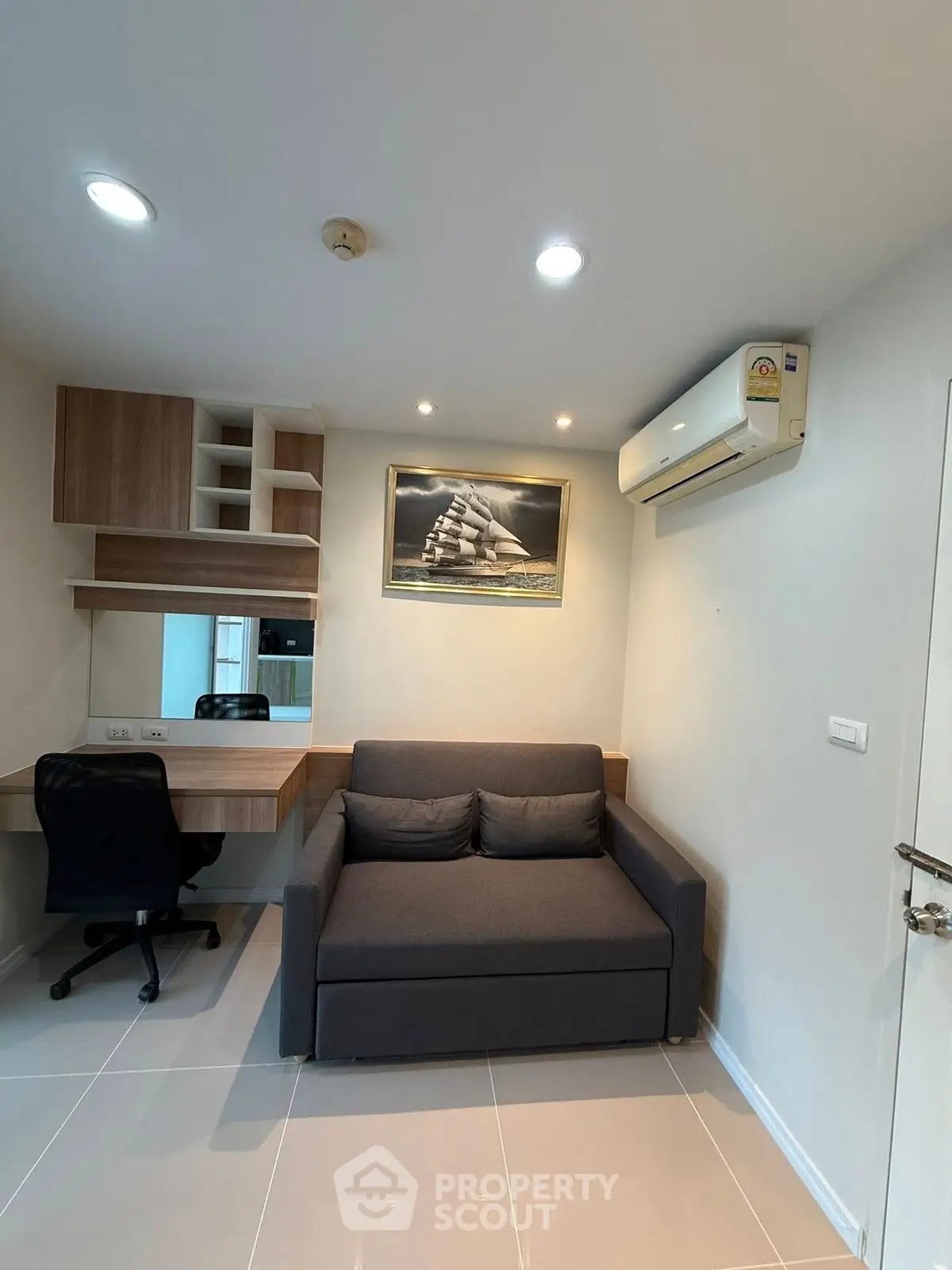 Modern study room with sleek desk, comfortable sofa, and air conditioning in a stylish apartment.