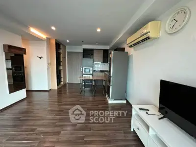 Modern open-plan living room with sleek kitchen and stylish furnishings in a contemporary apartment.