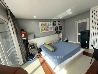 Sunlit bedroom with polished hardwood floors, modern furnishings, and access to a private balcony, perfect for urban living.