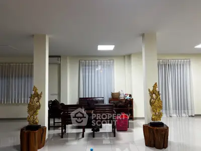 Expansive and elegant living room with polished tile flooring, classic wooden furniture, and tasteful artistic sculptures enhancing the luxurious ambiance.