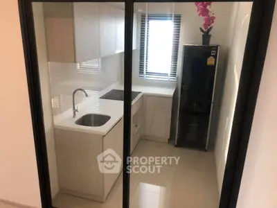 Modern compact kitchen with sleek cabinetry and black fridge