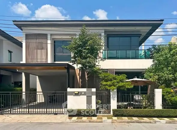 Modern two-story house with sleek design and spacious driveway in a suburban neighborhood.