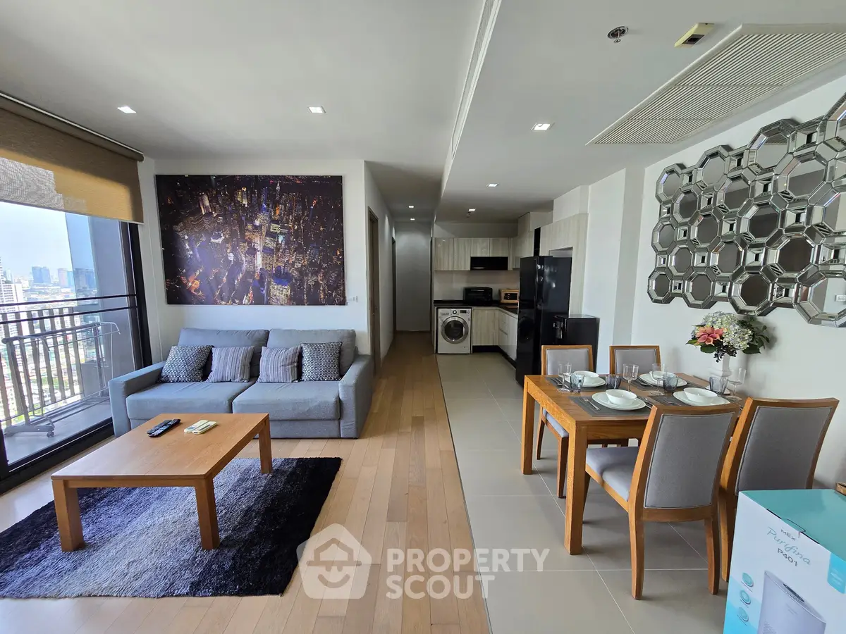 Modern open-plan living room with city view, stylish decor, and fully equipped kitchen in a high-rise apartment.