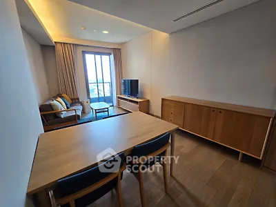 Modern living room with wooden furniture and large window offering natural light.
