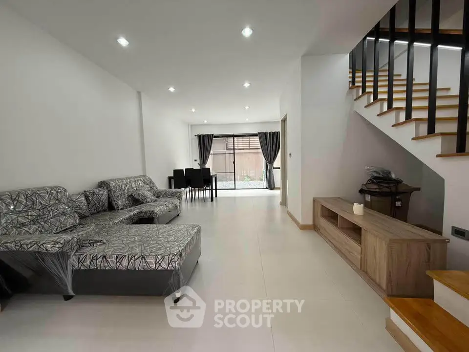 Spacious modern living room with stylish staircase and dining area, perfect for family gatherings.