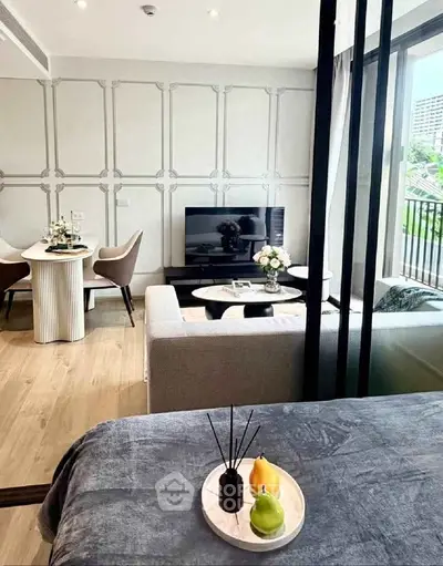 Modern living room with elegant decor and open dining area, featuring a large TV and stylish furniture.
