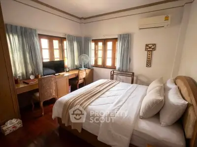Cozy bedroom with elegant wooden furniture and natural light from multiple windows.