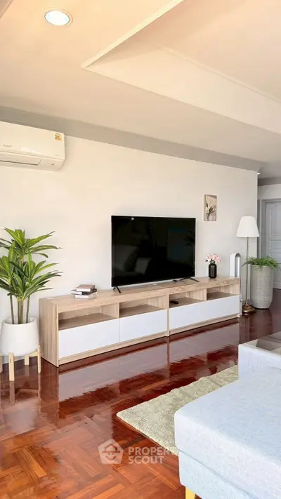 Modern living room with sleek TV stand, hardwood floors, and stylish decor.