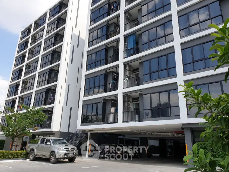 Modern apartment building with parking area and lush greenery