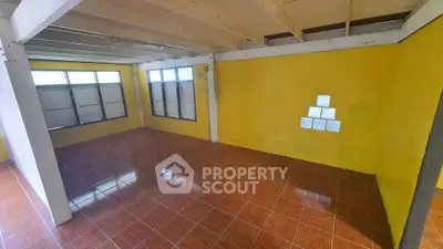 Spacious room with vibrant yellow walls and tiled flooring, featuring large windows for natural light.
