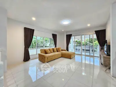 Spacious living room with modern decor and large windows overlooking greenery.