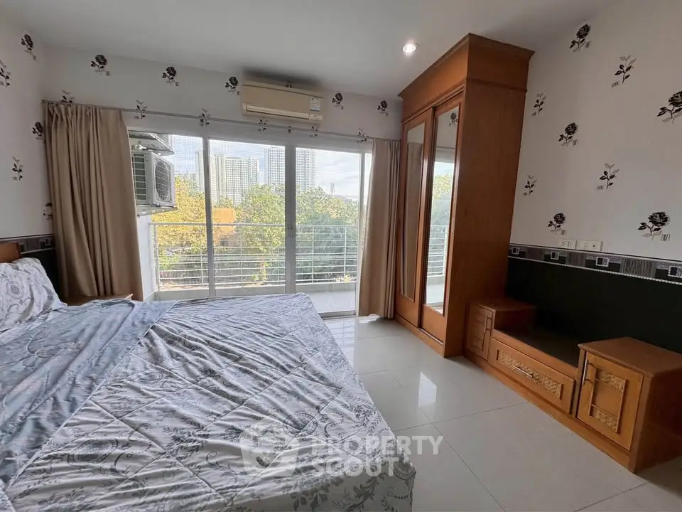 Spacious bedroom with balcony and city view, featuring elegant decor and ample natural light.