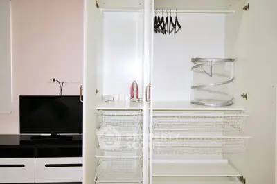 Spacious white wardrobe with wire baskets and hangers in modern bedroom.