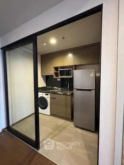 Modern kitchen with sleek appliances and washing machine in compact layout