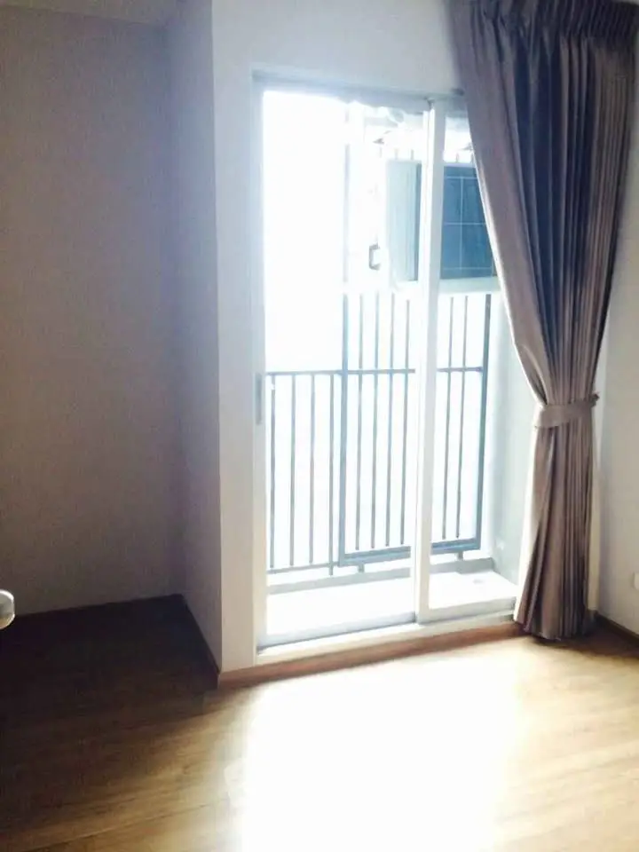 Bright room with sliding glass door leading to a small balcony, featuring elegant curtains and wooden flooring.