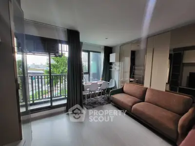 Modern living room with large windows and balcony access, featuring stylish furniture and natural light.