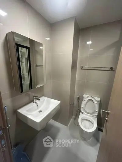 Modern bathroom with sleek fixtures and neutral tiles, featuring a wall-mounted sink and toilet.