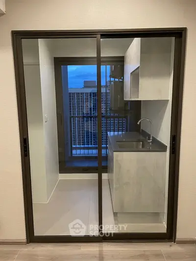 Modern kitchen with sleek cabinetry and sliding glass doors leading to a balcony with city view.