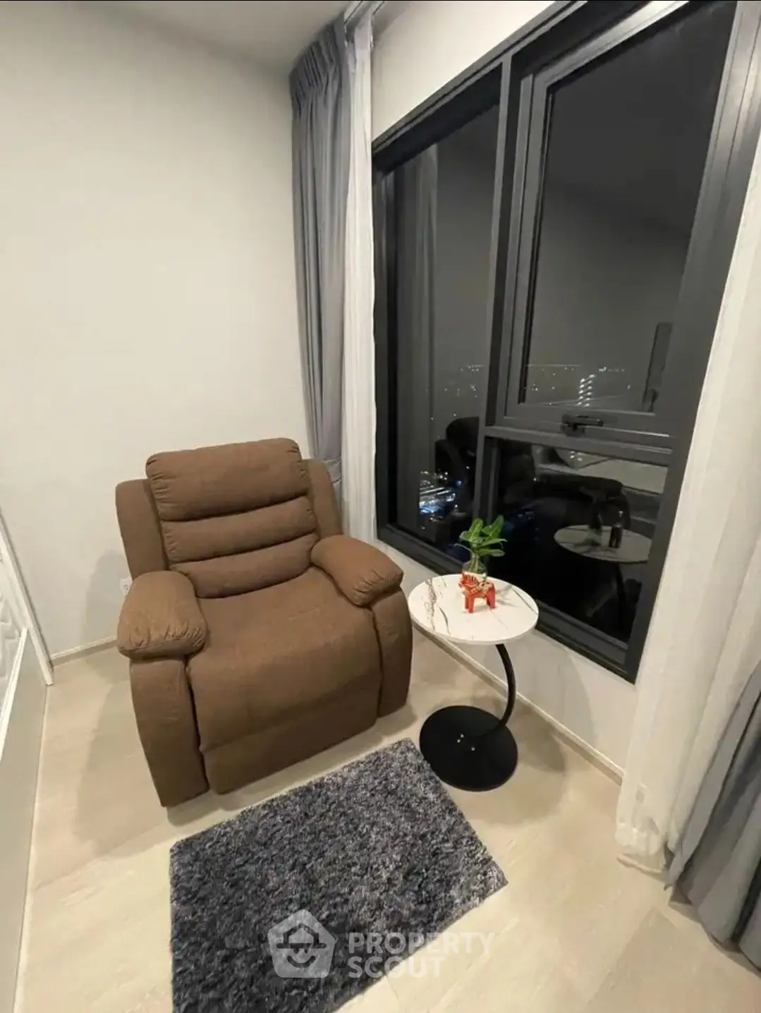 Cozy corner with plush armchair and city view, perfect for relaxation.