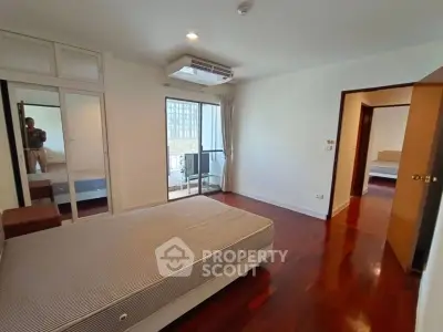 Spacious bedroom with hardwood floors and balcony access in modern apartment