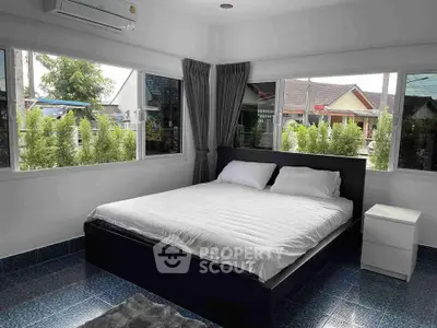Spacious bedroom with large windows and modern decor in a serene residential area.