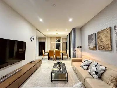Modern living room with stylish decor and open dining area, featuring a cozy sofa and wall art.