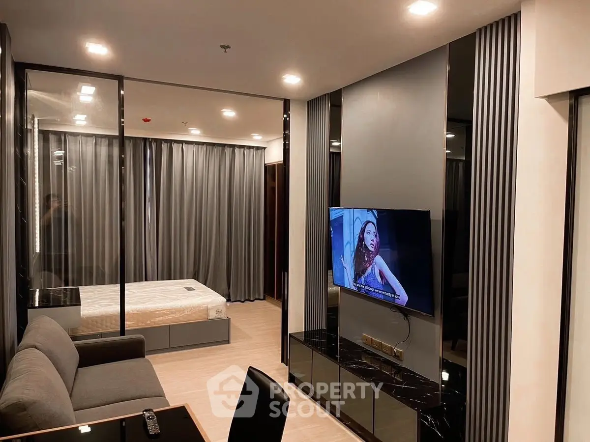 Modern studio apartment with sleek design, featuring a cozy living area and a stylish bedroom separated by glass panels.